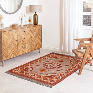Jute kilim rug in living room with wooden sideboard, lamp.